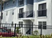 Thumbnail 30 of 31 - an apartment building with a red car parked in front of it